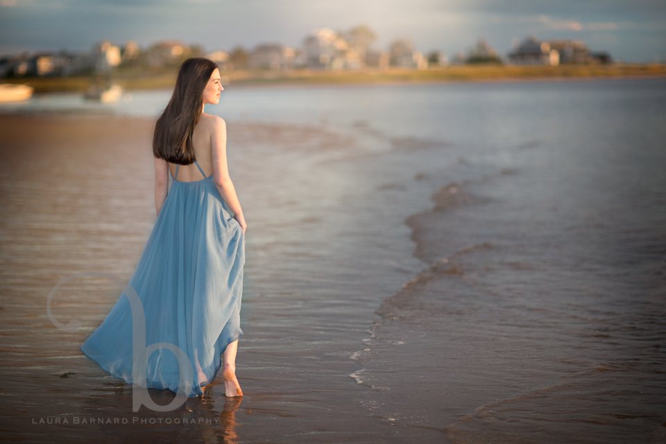 A senior portrait session walking into the surf at sunset in a blue dress.